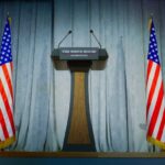 Trump Vows Safe Chicago — In One Month Podium between two American flags on a stage