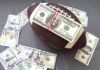 Football with a stack of U.S. hundred-dollar bills secured by rubber bands