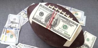 Football with a stack of U.S. hundred-dollar bills secured by rubber bands