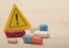 Pills with warning sign in background