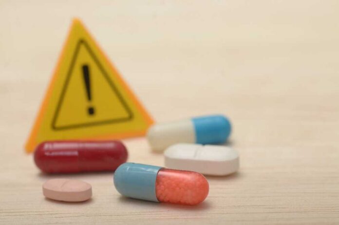 The,Danger,Of,Drug,Abuse:,Warning,Signs,And,Pill,Capsules Pills with warning sign in background