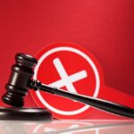 Judge's gavel with a red cross symbol in the background