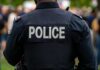 Back view of a police officer wearing a uniform with 'POLICE' displayed
