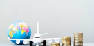 Stacked coins in front of a toy airplane and globe