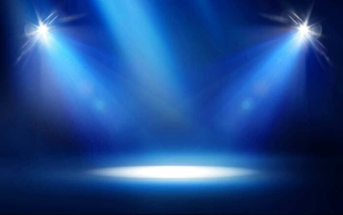 shutterstock_529365124 Empty stage with blue spotlights shining down.
