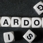 Trump Pardon Twist Explodes In Clancy Case White letter blocks spelling 'PARDON' on a black surface