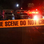 Toddler Dead, Mom Charged — Horrific Details Crime scene tape with emergency vehicles in background.