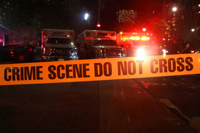 shutterstock_746018290-2 Crime scene tape with emergency vehicles in background.