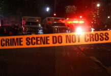 Toddler Dead, Mom Charged — Horrific Details Crime scene tape with emergency vehicles in background.
