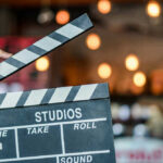 Evil Dead Icon Drops Chilling Cancer Timeline Hand holding a movie clapperboard in studio setting.