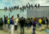 Hundreds of Illegals March North – DHS On Alert People sit atop a border wall during protest.