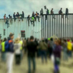 Hundreds of Illegals March North – DHS On Alert People sit atop a border wall during protest.