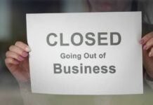 A person holding a sign that reads 'CLOSED Going Out of Business'