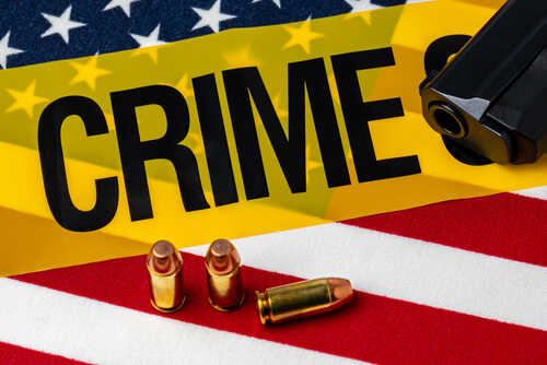 A gun and bullets on an American flag with a crime scene marker