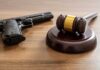 Bombshell Lawsuit: Five Bullets – Three Cams Judge's gavel and handgun on wooden table