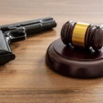 Bombshell Lawsuit: Five Bullets – Three Cams Judge's gavel and handgun on wooden table