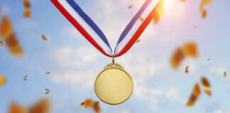 Gold medal with blue, white, red ribbon, sky background.