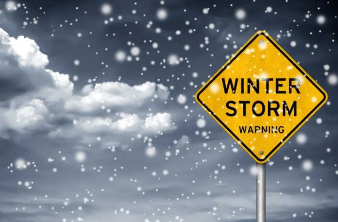Winter,Storm,Warning,-,Road,Sign,Information A yellow warning sign indicating a winter storm amidst falling snow