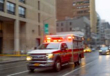 100-Foot Plunge – She’s Found Alive Ambulance with flashing lights driving on a wet city street