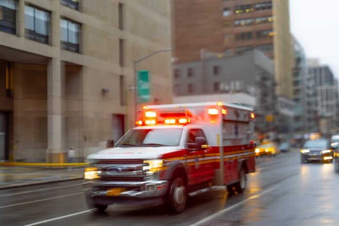 A,Blurred,Ambulance,Races,Through,The,Bustling,Streets,Of,New Ambulance with flashing lights driving on a wet city street