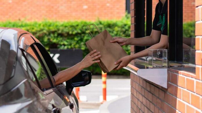 drive-thru window handing a paper bag to a driver