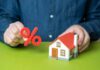 Mortgage Shock Freezes Buyers Person holding a percentage symbol above a model house