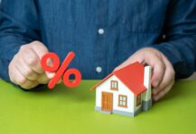 Mortgage Shock Freezes Buyers Person holding a percentage symbol above a model house