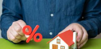 Person holding a percentage symbol above a model house