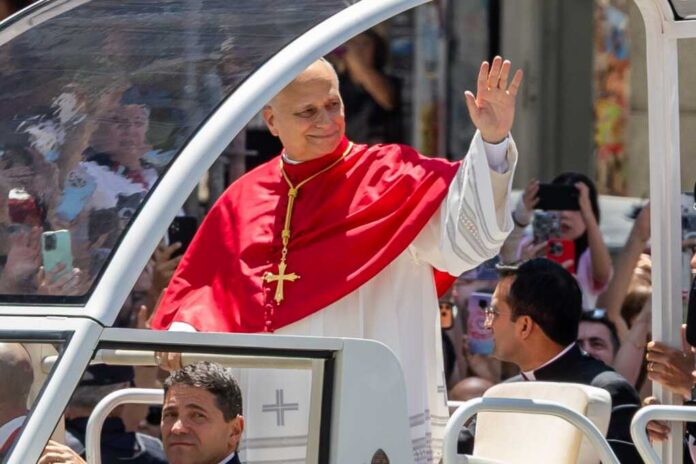 Catholic clergyman in red vestments waving from a popemobile