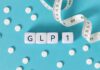 GLP-1 cubes with pills and a measuring tape on blue background