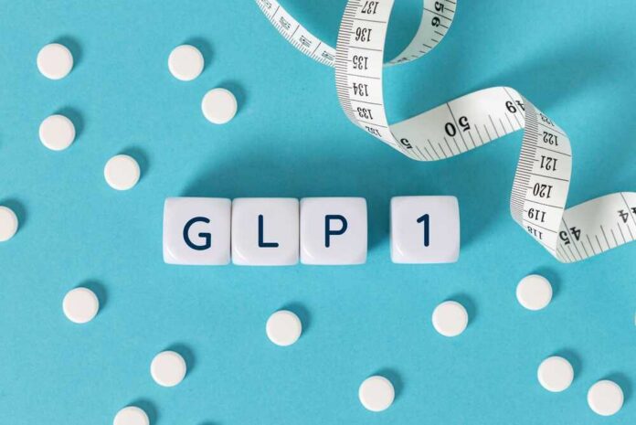 Glp,1,Word,On,Blocks,Surrounded,By,Medicine,Pills,And GLP-1 cubes with pills and a measuring tape on blue background