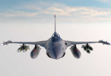 Fighter jet banking in flight with vapor trails
