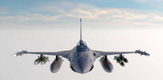 Fighter jet banking in flight with vapor trails