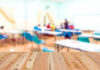 Teachers Bankroll Progressives Blurred classroom with students and a wooden foreground.