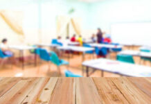 Blurred classroom with students and a wooden foreground.