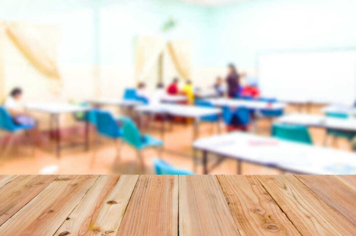 shutterstock_486538096 Blurred classroom with students and a wooden foreground.